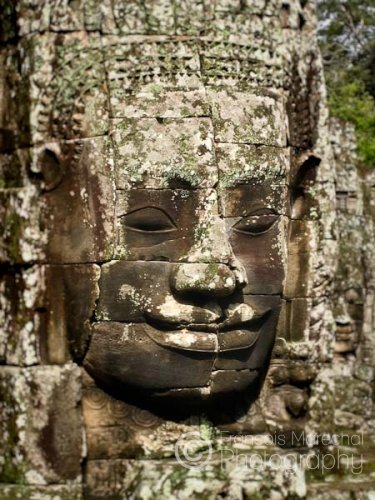 Carved stone faces gaze down from the towers of the Bayon temple. The Buddhist temple was constructed for Jayavaraman VII in the late 12th to early 13th century. It lies in the centre of the capital city, Angkor Thom.
